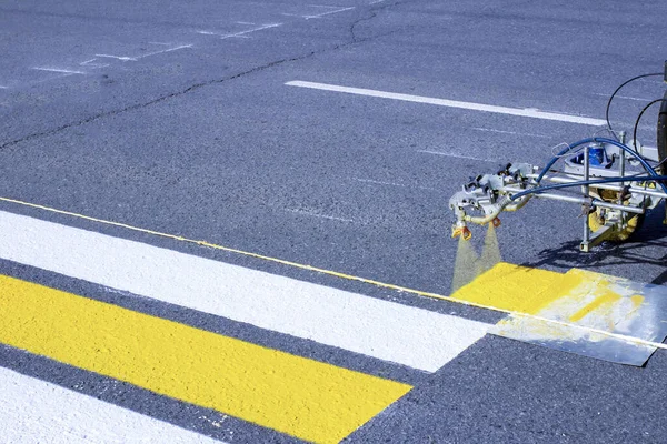 一队工人在早春用新型沥青上的自动化设备在人行横道上画画 图库图片