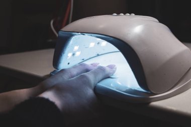 Shellac kaplamalı manikür. Ultraviyole lambada kurutma işlemi.