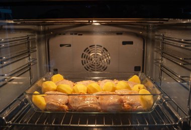 Tavuk butları ve patatesler fırında yakın plan ızgarada.