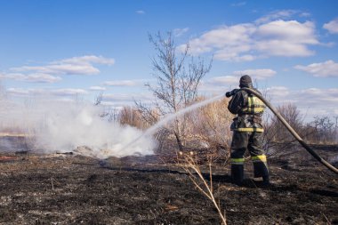 İtfaiyeci baharda ölü odunları söndürür..
