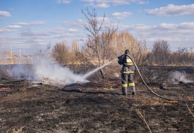 İtfaiyeci baharda ölü odunları söndürür..