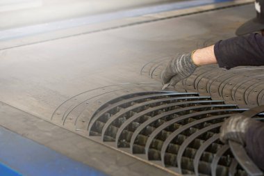 Bir adam elleri ile bir CNC makinesi tarafından çelik işleme atölyesinde metal için yapılan atölyeleri çıkarıyor.