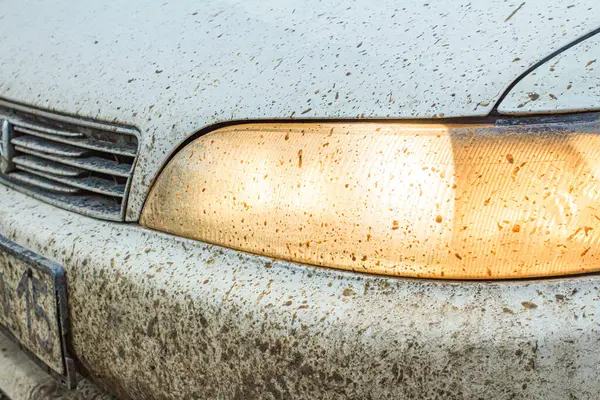 very dirty car headlight close-up, during bad weather on a dirty road, problem with lighting and visibility on the highway