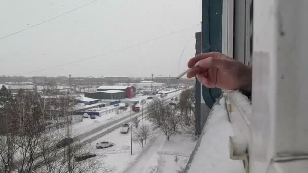 雪の背景と冬の日との高層ビルの窓から喫煙 最初の人 — ストック動画