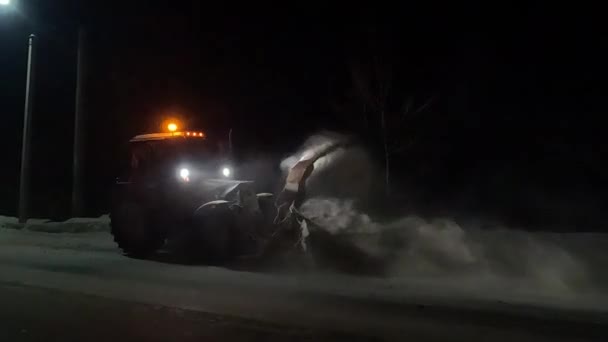 夜間に動作するトラクターの形で雪除去装置を投げ 溝に道路から雪を投げます — ストック動画