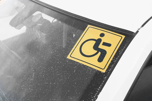 A sticker on the windshield of a car warning that the driver is a disabled driver with disabilities.