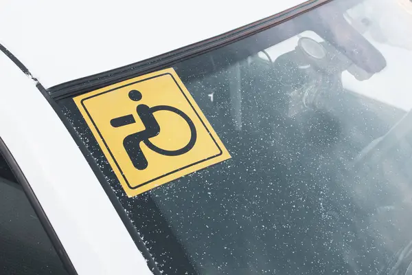 A sticker on the windshield of a car warning that the driver is a disabled driver with disabilities.