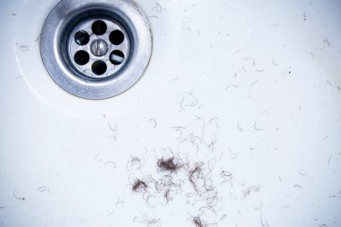Banyo lavabosunun duvarlarında kalan tıraş ve tüy dökümünden sonra kasık bölgesinin mahrem bölgelerinden alınan kıllar, yakın çekim dokusu.