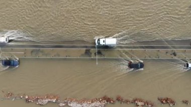 Su baskınları ve sel baskınları sırasında su basmış bir otoyol boyunca giden araba ve kamyonlar yağmurlar ve karlı hava aracından çekilen erimiş su akıntısı