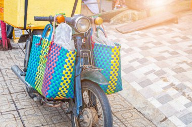 Asya 'da eski bir benzin motorunun içinde büyük bir valiz taşımak, gidonun üzerinde çantalar olan bir motosikleti kapatmak.