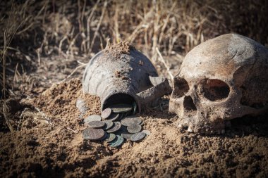 Eski bir yerleşim yerinde metal detektör kullanılarak yapılan bir aramada bulunan bir sürahide bulunan antik madeni para birikintisi ve antik bir şehirdeki bir mezarlıkta bulunan doğal bir kafatası.