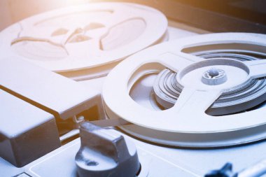 Stüdyonun arka planında, mavi pembe ışık ve dumanlı bir teyp var. Müzik çalmak için manyetik teybi olan analog antika müzik çalar. Karanlıktaki eski çember bobbin. Kapat..