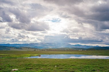Güneş ışınları kümülüs bulutlarının arasından karla kaplı dağların tepelerine ve medeniyetin dışında şehirlerden uzakta berrak bir göle doğru yükseliyor.