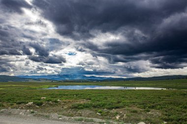 Güneş ışınları kümülüs bulutlarının arasından karla kaplı dağların tepelerine ve medeniyetin dışında şehirlerden uzakta berrak bir göle doğru yükseliyor.