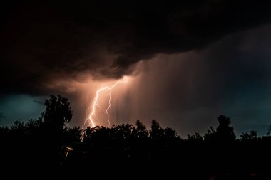 Gece gök gürültülü bir fırtınada, karanlık gökyüzüne karşı, bir yangına neden olan bir ormanda, yağmurlu bir fırtınada güzel bir yıldırım.