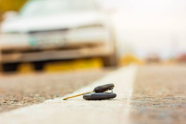 Altın sonbaharda, gün batımında bulanık bir arabanın arka planına karşı koyan şehir yolundaki bir yolda kaybolmuş anahtarlar.