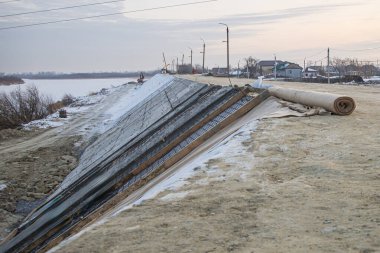 construction of a protective dam using roll materials and concrete to protect against spring floods and melt waters clipart