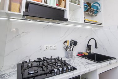 İskandinav mutfağındaki gri mobilyalı boş ahşap masa. Dairesinde çeşitli kavanozlar ve sofra takımları olan tezgah ve minimalist parlak iç mekan..