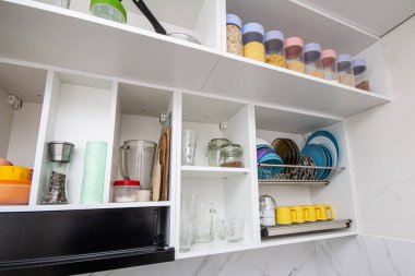 İskandinav mutfağındaki gri mobilyalı boş ahşap masa. Dairesinde çeşitli kavanozlar ve sofra takımları olan tezgah ve minimalist parlak iç mekan..