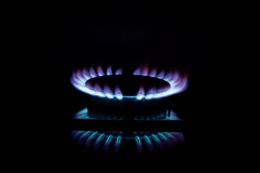 Siyah arka planda yanan bir gaz ocağı üzerine yüz dolarlık banknot, ön ve arka planda bokeh etkisi ile bulanıklaştırılmış.
