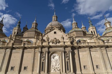 Parlak mavi gökyüzünün altında heykellerle süslenmiş Basilica del Pilar 'ın Barok cephesinin büyük ön görüntüsü.