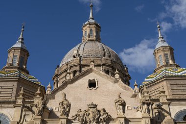 Parlak mavi gökyüzünün altında heykellerle süslenmiş Basilica del Pilar 'ın Barok cephesinin büyük ön görüntüsü.