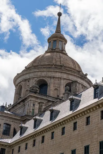 stock image Sculptural details and the iconic dome of El Escorial Monastery stand out against a blue sky with fluffy clouds