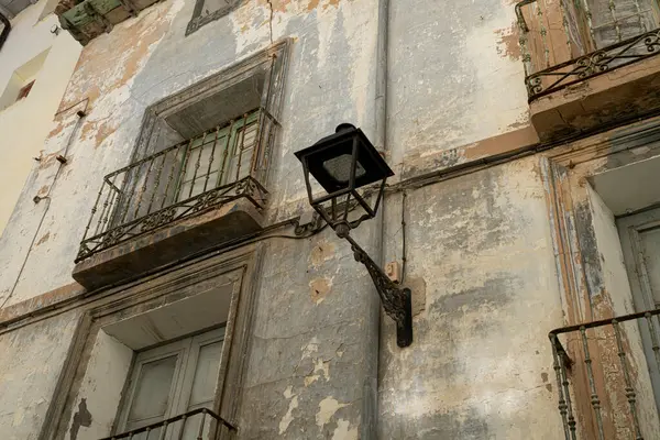 一盏旧路灯挂在一座漆成剥皮的建筑物上 凸显了城市衰败的乡村魅力 图库照片