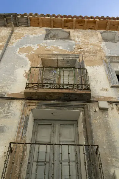 一座古旧的阳台的特写 阳台上有华丽的栏杆 旁边是一座年久失修的城市建筑 墙壁摇摇欲坠 图库图片
