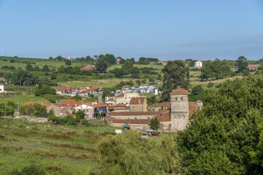 İspanya 'nın Cantabria kentindeki Santillana del Mar kentinin panoramik manzarası. Manzarada geleneksel taş binalar, yemyeşil alanlar ve açık mavi bir gökyüzü yer alıyor..