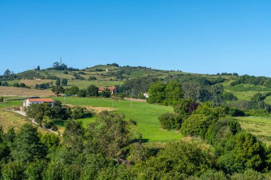 İspanya 'nın Cantabria kentindeki Santillana del Mar kentinin panoramik manzarası. Manzarada geleneksel taş binalar, yemyeşil alanlar ve açık mavi bir gökyüzü yer alıyor..