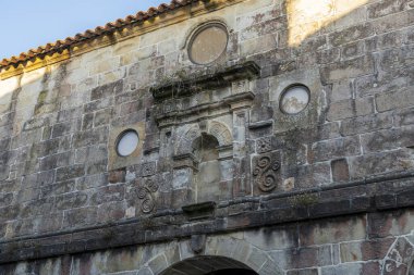 Santillana del Mar, Cantabria, İspanya 'daki tarihi çan kulesinin yakın görüntüsü. Antik taş mimarisi açık mavi gökyüzüne karşı duruyor..