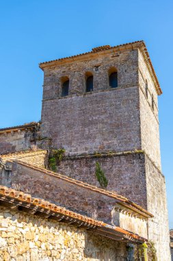 Santillana del Mar, Cantabria, İspanya 'daki Santa Juliana Kolej Kilisesi' nin çan kulesine yakın çekim. Ortaçağ taş mimarisi açık mavi gökyüzüne karşı duruyor..