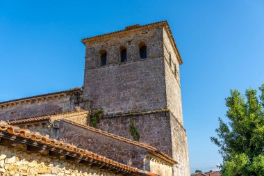 Santillana del Mar, Cantabria, İspanya 'daki Santa Juliana Kolej Kilisesi' nin çan kulesine yakın çekim. Ortaçağ taş mimarisi açık mavi gökyüzüne karşı duruyor..