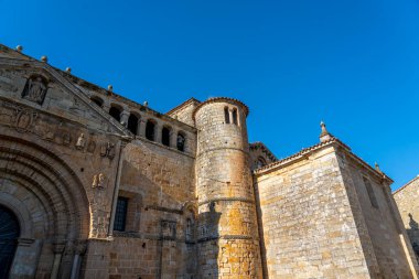 Santillana del Mar, Cantabria, İspanya 'daki Santa Juliana Kolej Kilisesi' nin çan kulesine yakın çekim. Ortaçağ taş mimarisi açık mavi gökyüzüne karşı duruyor..