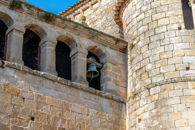 Santillana del Mar, Cantabria, İspanya 'daki Santa Juliana Kolej Kilisesi' nin çan kulesine yakın çekim. Ortaçağ taş mimarisi açık mavi gökyüzüne karşı duruyor..