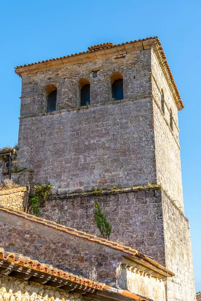 stock image Close-up of the bell tower of the Collegiate Church of Santa Juliana in Santillana del Mar, Cantabria, Spain. The medieval stone architecture stands against a clear blue sky.