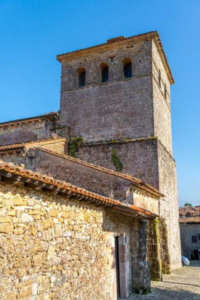 stock image Close-up of the bell tower of the Collegiate Church of Santa Juliana in Santillana del Mar, Cantabria, Spain. The medieval stone architecture stands against a clear blue sky.