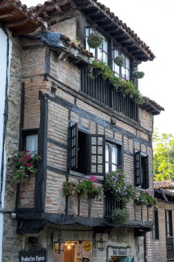 İspanya, Santillana del Mar 'da taştan yapılma antika bir cadde. Taştan binalar ve çiçeklerle süslenmiş balkonları var. Seyahat, mimari ve kültürel temalar için ideal