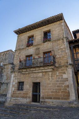 İspanya, Santillana del Mar 'da taştan yapılma antika bir cadde. Taştan binalar ve çiçeklerle süslenmiş balkonları var. Seyahat, mimari ve kültürel temalar için ideal
