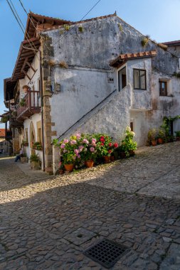 İspanya, Santillana del Mar 'da taştan yapılma antika bir cadde. Taştan binalar ve çiçeklerle süslenmiş balkonları var. Seyahat, mimari ve kültürel temalar için ideal