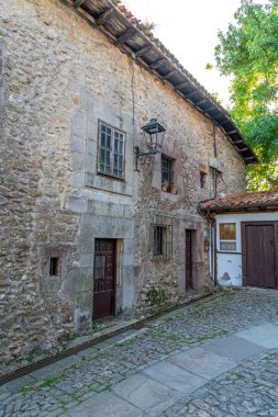 İspanya, Santillana del Mar 'da taştan yapılma antika bir cadde. Taştan binalar ve çiçeklerle süslenmiş balkonları var. Seyahat, mimari ve kültürel temalar için ideal
