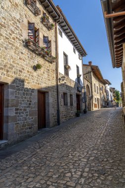 İspanya, Santillana del Mar 'da taştan yapılma antika bir cadde. Taştan binalar ve çiçeklerle süslenmiş balkonları var. Seyahat, mimari ve kültürel temalar için ideal