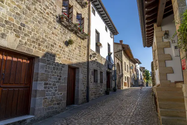 İspanya, Santillana del Mar 'da taştan yapılma antika bir cadde. Taştan binalar ve çiçeklerle süslenmiş balkonları var. Seyahat, mimari ve kültürel temalar için ideal