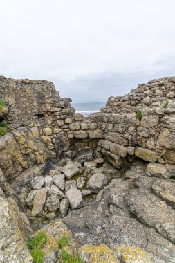 İspanya 'nın Cantabria kentindeki engebeli bir uçuruma tünemiş tarihi taş kalıntılarının büyüleyici manzarası. Arka planda okyanus var. Seyahat, tarih ve manzara temaları için ideal.