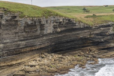İspanya, Cantabria 'da denize bakan, katmanlı kaya oluşumları ve yemyeşil yeşillikleri olan görkemli sahil kayalıkları. Manzara, seyahat ve doğa temaları için mükemmel..
