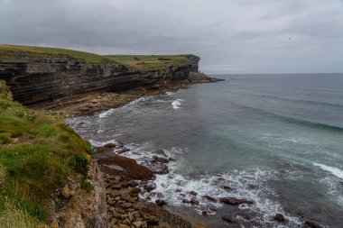 İspanya, Cantabria 'da denize bakan, katmanlı kaya oluşumları ve yemyeşil yeşillikleri olan görkemli sahil kayalıkları. Manzara, seyahat ve doğa temaları için mükemmel..