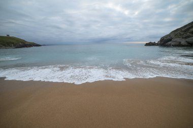 Tranquil scene of Tagle Beach in Cantabria, Spain, showcasing rugged rocks, gentle waves, and an expansive horizon. Perfect for travel, nature, and coastal themes. clipart