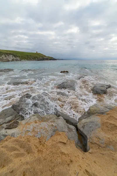 stock image Tranquil scene of Tagle Beach in Cantabria, Spain, showcasing rugged rocks, gentle waves, and an expansive horizon. Perfect for travel, nature, and coastal themes.