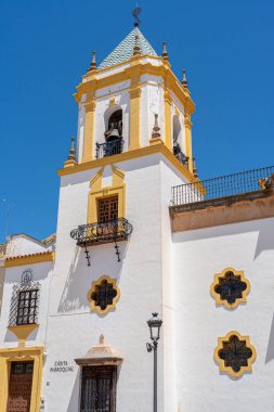 İspanya 'nın Ronda kentindeki Nuestra Senora de la Merced Kilisesi' nin göz kamaştırıcı cephesinde, parlak mavi gökyüzünün altında ikiz çan kuleleri ve merkezi bir çeşme bulunuyor. İspanyol mimarisi, dini simgeler ve kültür turizmi için mükemmel bir tema.